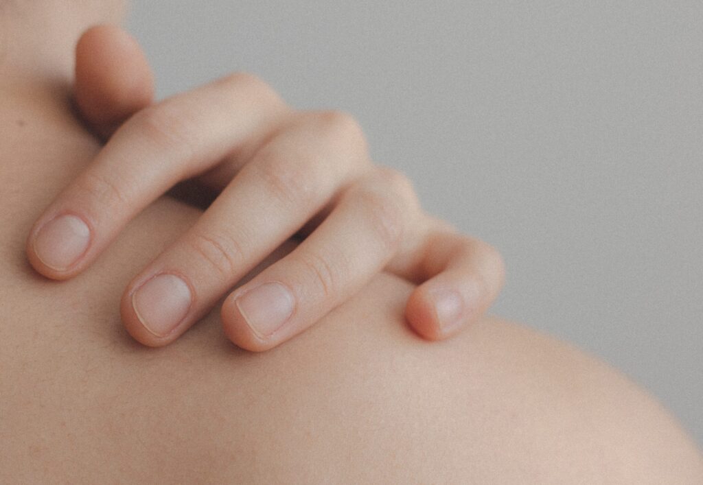 Hand auf nackter Schulter nach der Nagelpflege