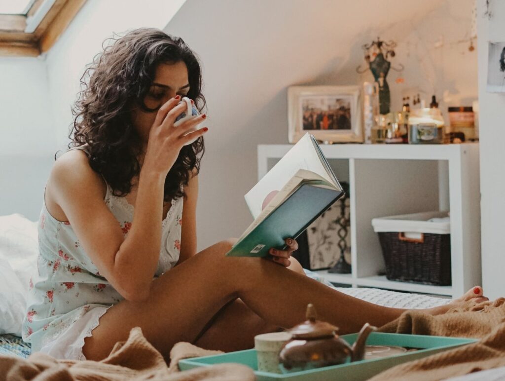 Eine Frau trinkt Tee und liest ein Buch.