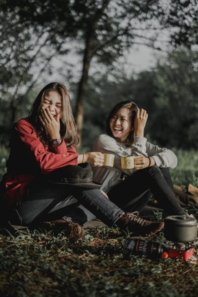 Zwei Frauen sitzen in der Natur und lachen