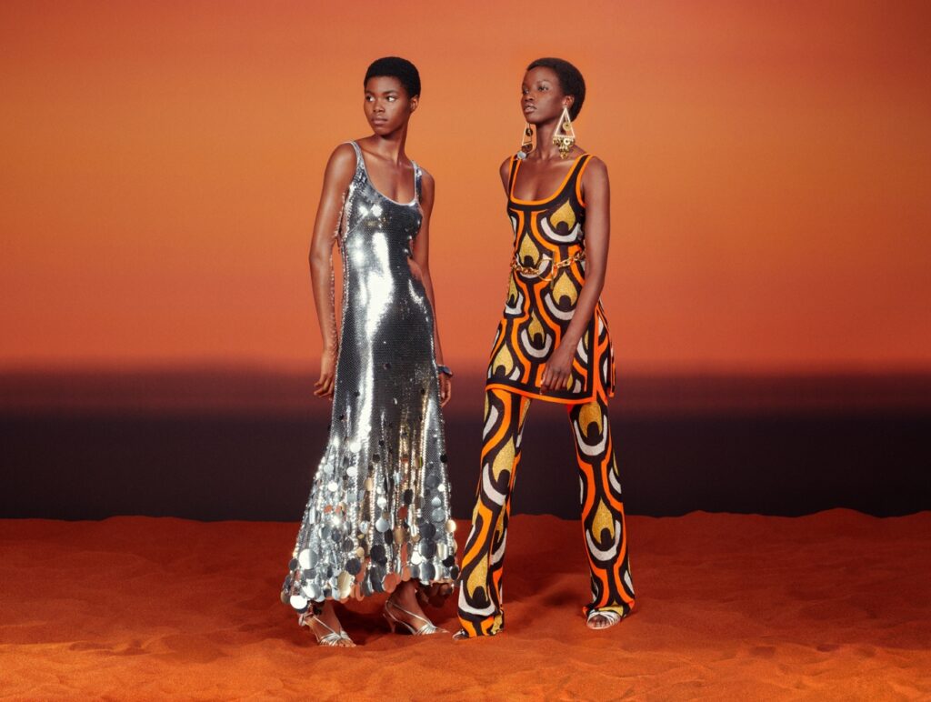Zwei Models stehen vor einem Hintergrund in Orange und tragen Rabanne x H&M.
