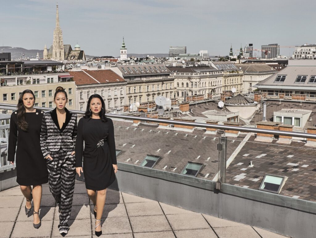 Ina Jovanovic, Miriam Hie und Nadja Maleh gehen auf die Kamera zu. Sie stehen auf einer Dachterrasse in Wien.