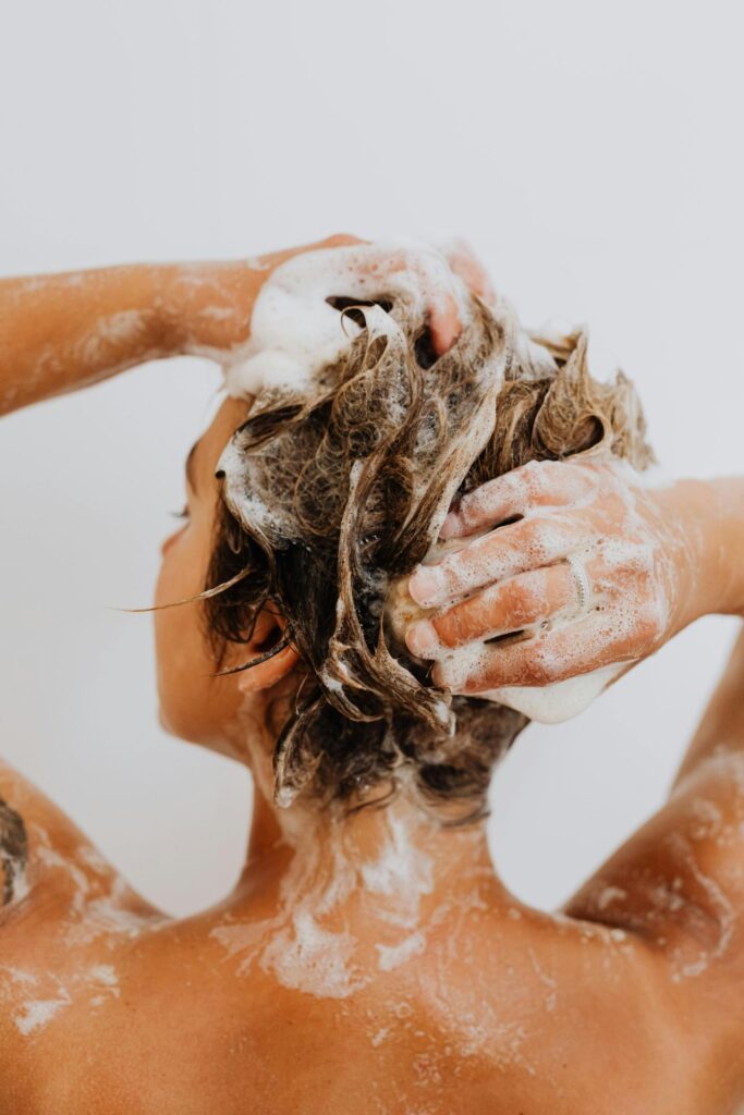 Frau wascht sich die Haare mit Shampoo