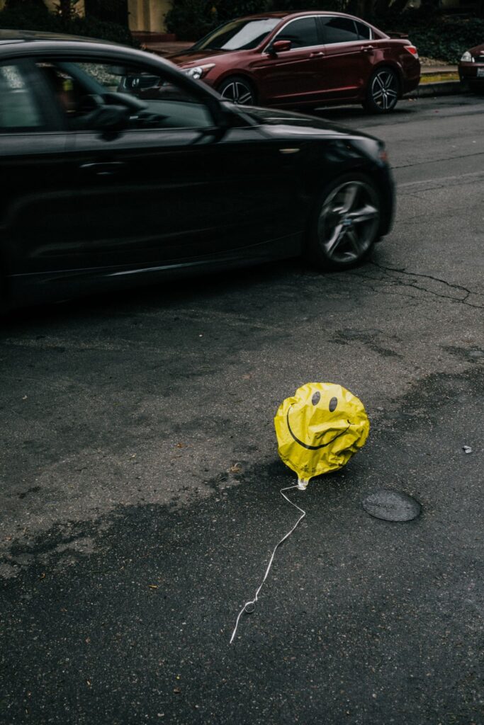 Gelber Smiley Luftballon liegt ohne Luft auf der Straße 