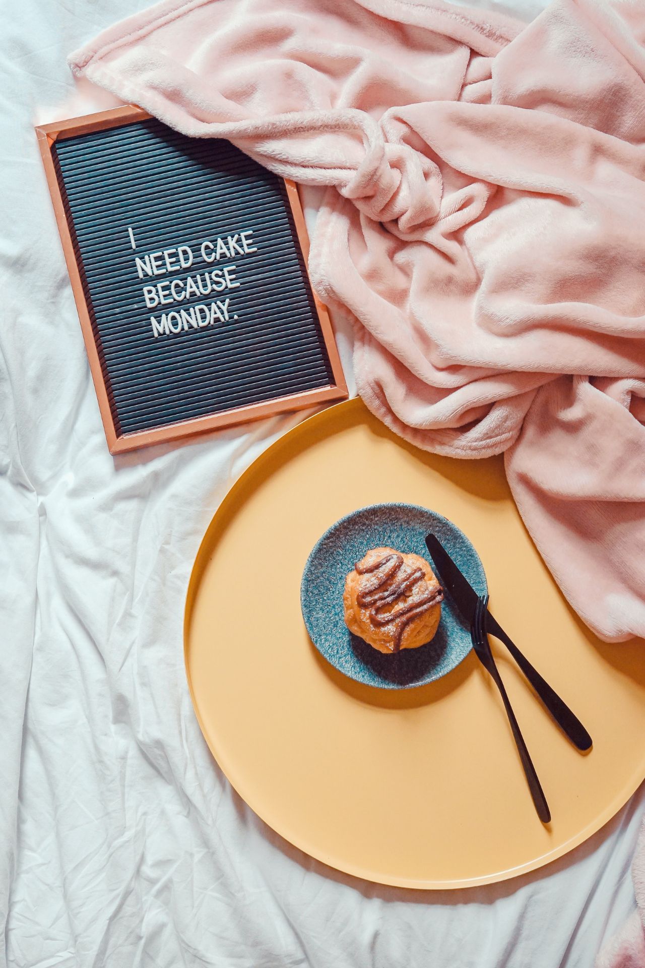 Sunday Blues: Muffin im Bett, dazu eine rosa Kuscheldecke und eine schwarze Tafel mit Spruch in weißen Lettern: "I need cake because Monday".