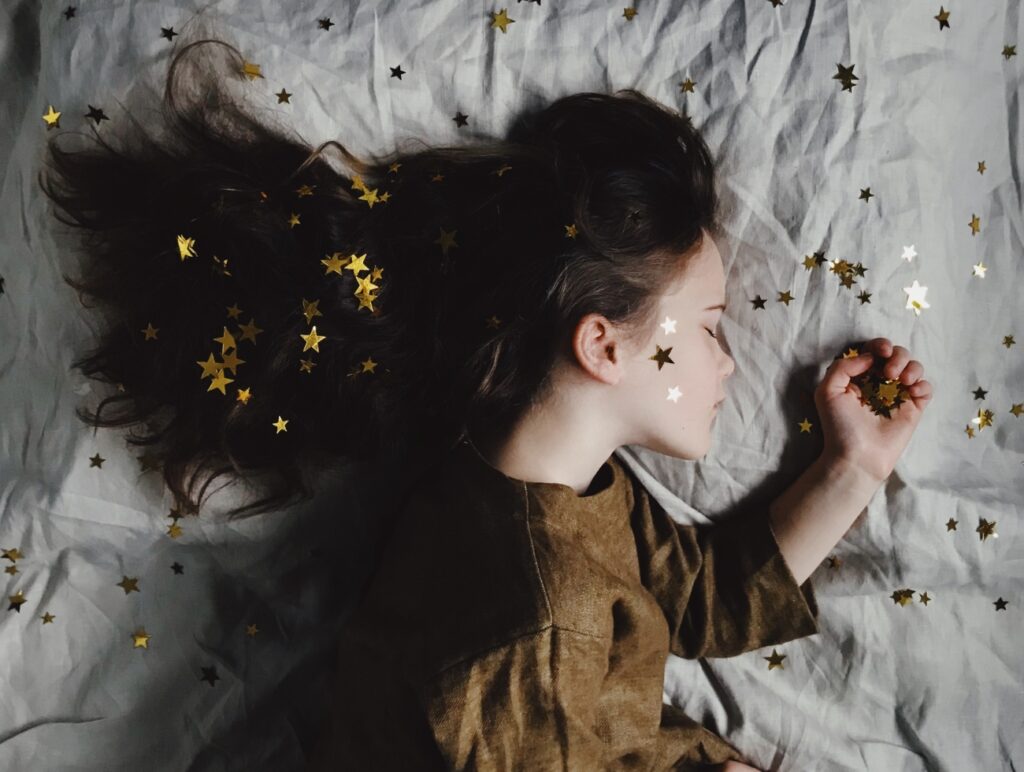Kind liegt im Bett mit Sternen in den haaren
