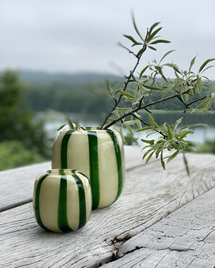 Grüne Vase mit Streifen auf einem Tisch in der Natur