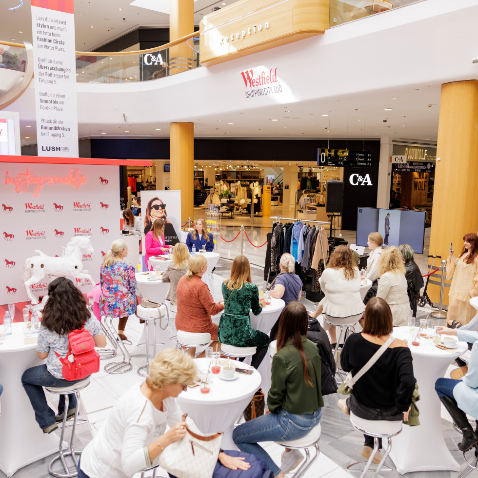 WSCS Fashion Circle mit der WIENERIN: Die Besucherinnen sitzen bei weißen Tischen und lauschen dem Talk von Sarah Lehner und Lisa Staltner