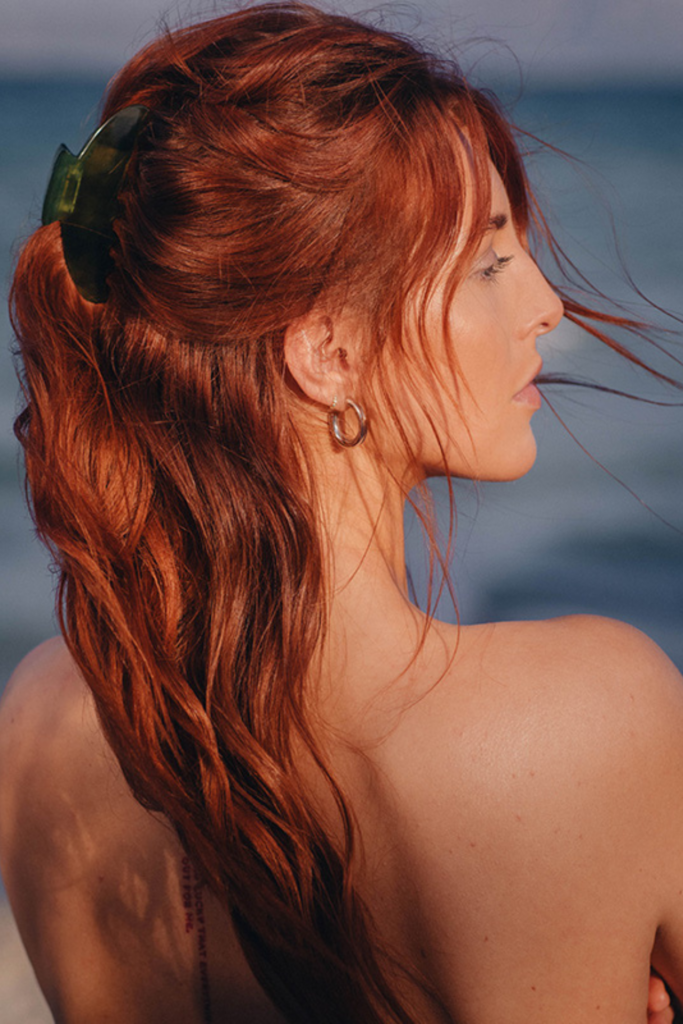 Eine Frau mit roten Haaren blickt aufs Meer