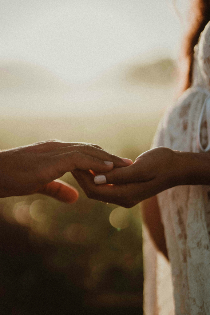 Eine schwangere Frau hält in der Abendsonne die Hand eines Mannes