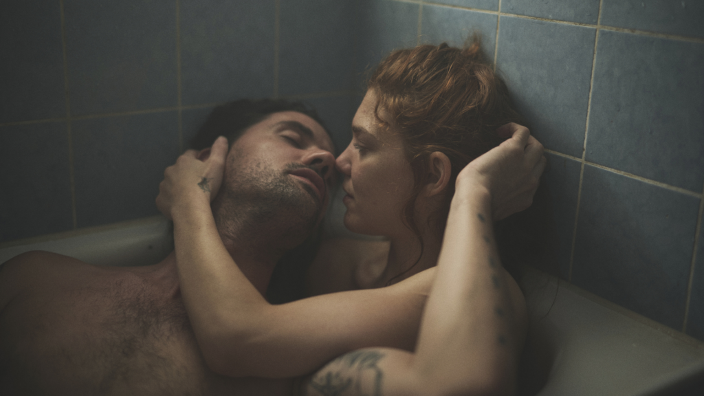 Ein Mann und eine Frau liegen in der Badewanne und küssen sich fast