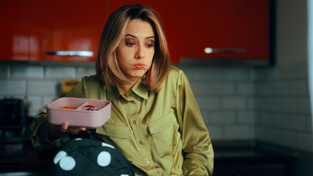 Gestresste Mutter packt die Lunchbox für ihr Schulkind