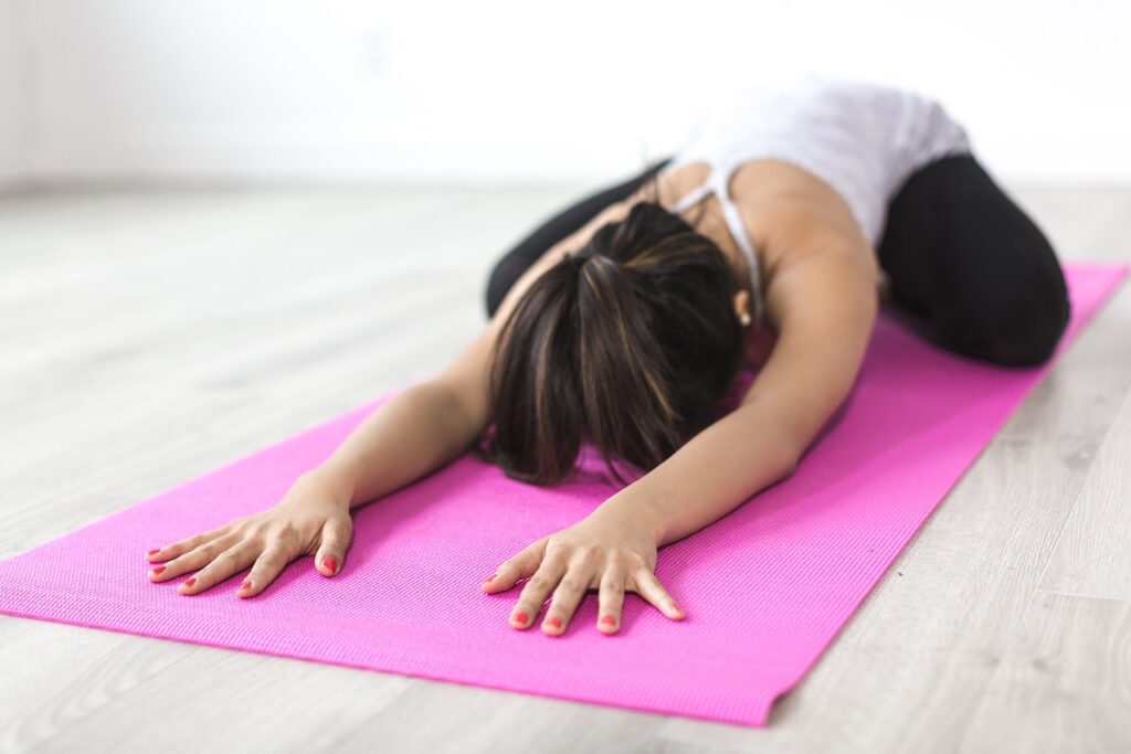Eine Frau dehnt sich auf einer Yoga Matte