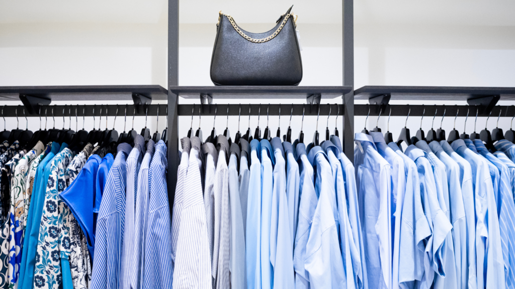 Blusen auf Kleiderbügeln, darüber liegt eine Tasche