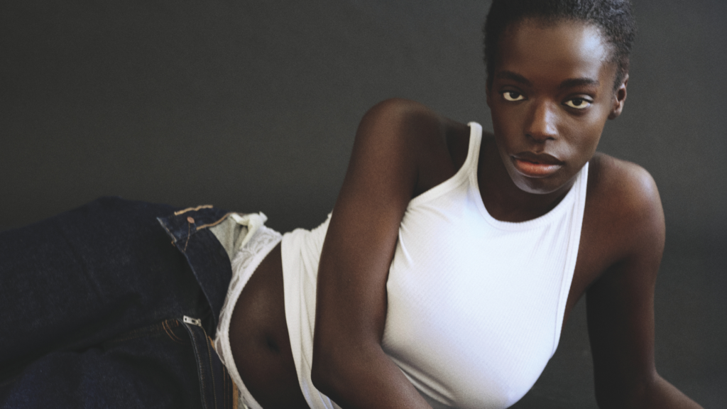 Model in weißem Tanktop und Jeans blickt in die Kamera