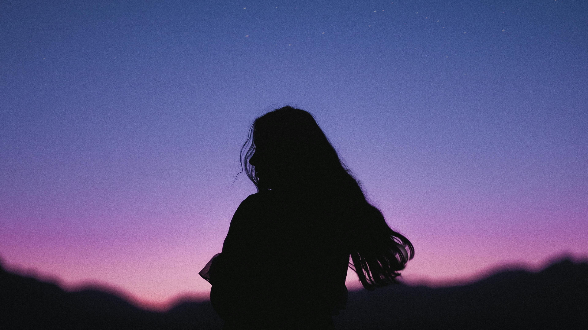 Frau steht vor buntem Sternehimmel