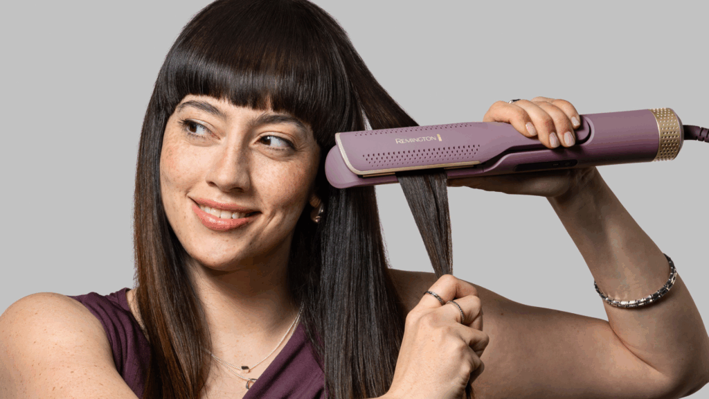 Der AIRvive 2-in-1 Airstyler in Violett und Gold von Remington an einer Haarsträhne einer dunkelhaarigen Frau