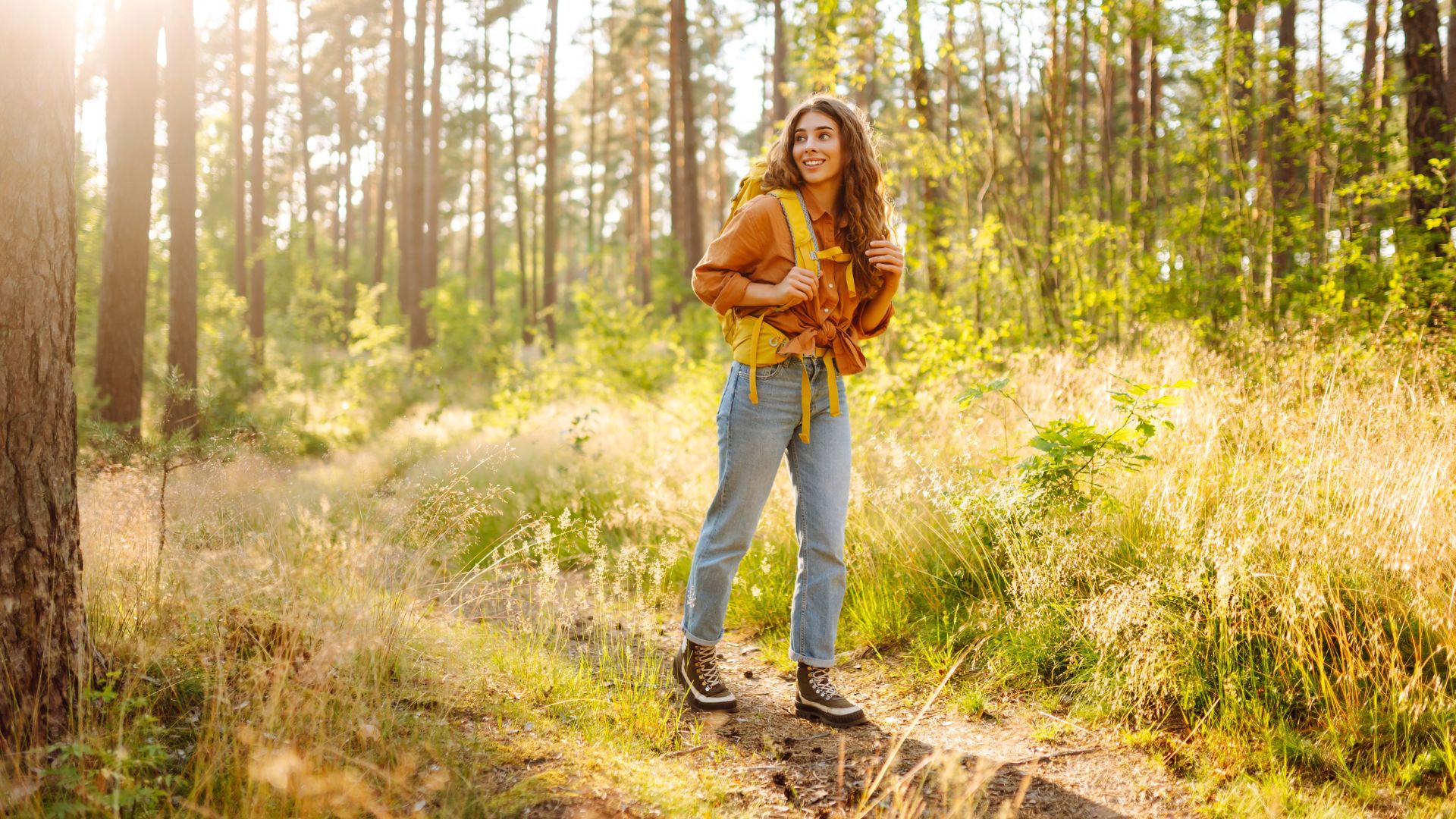 Junge Frau geht im Wald bei Sonneschein spazieren