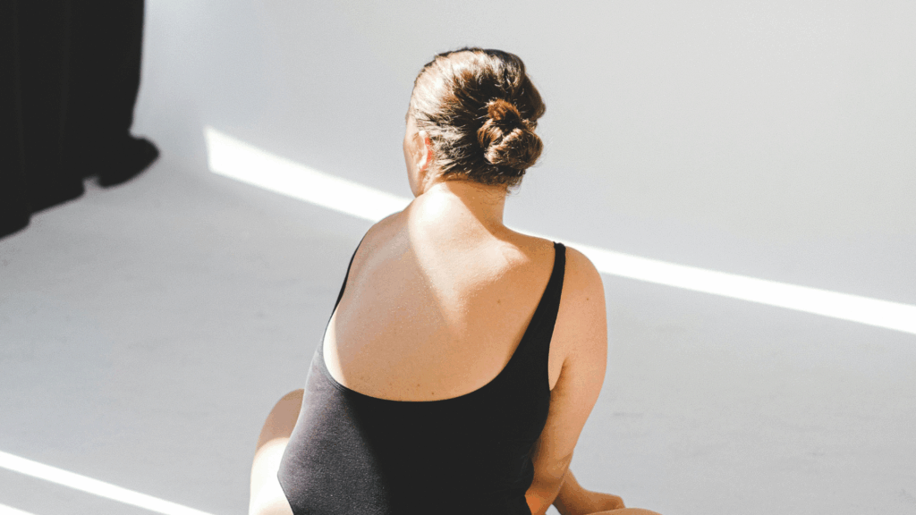 Eine Frau sitzt in schwarzem Body auf dem Boden