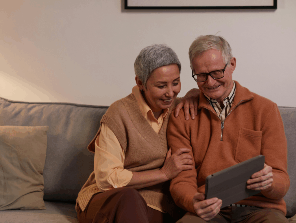 Eine Frau und ein Mann sitzen auf einem Sofa und schauen auf ein Tablet