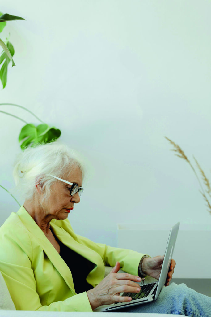 Eine Frau sitzt seitlich und arbeitet auf einem Laptop