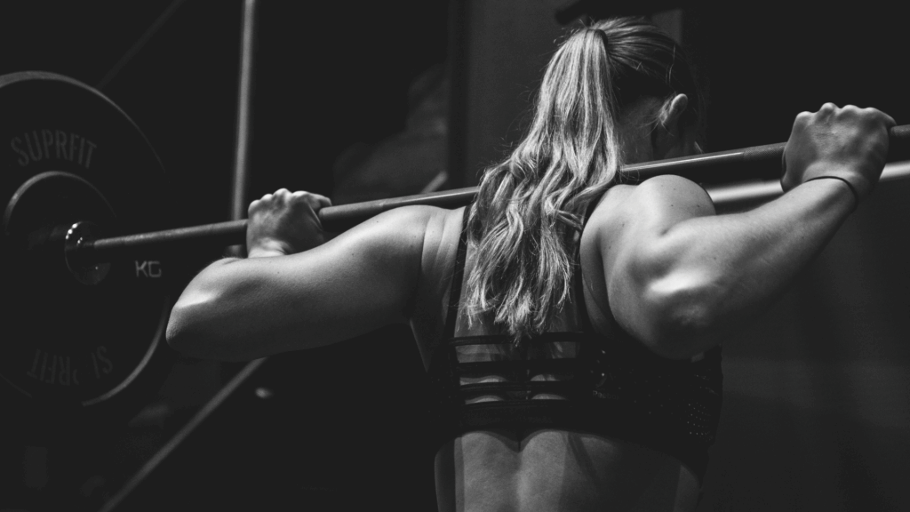 Frau von hinten mit einer Langhantel auf den Schultern