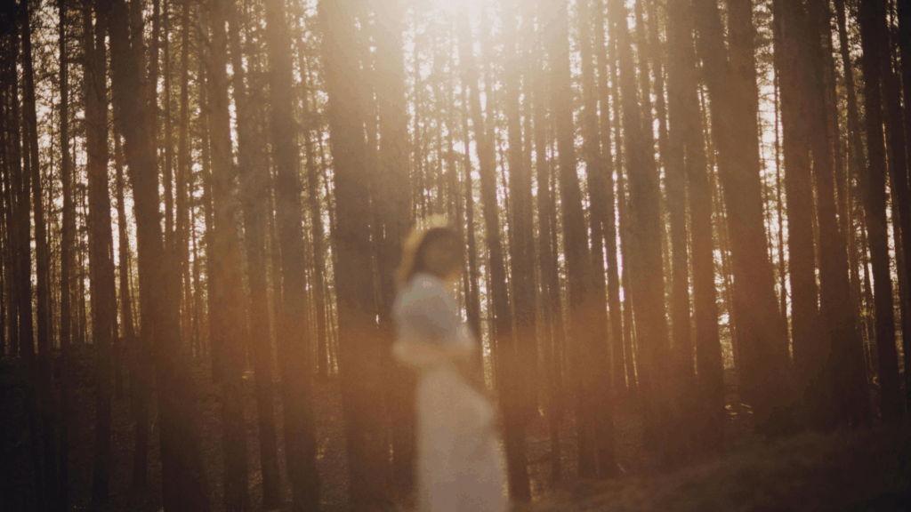 Eine verschwommene Silhouette einer Frau im Wald mit Sonnenstrahlen