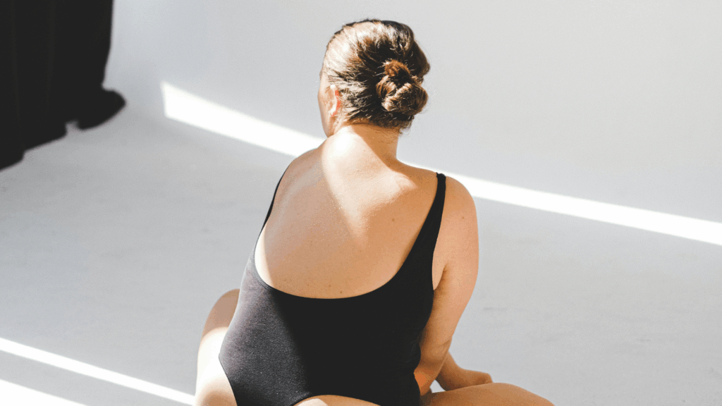 Eine Frau sitzt im Body auf dem Body