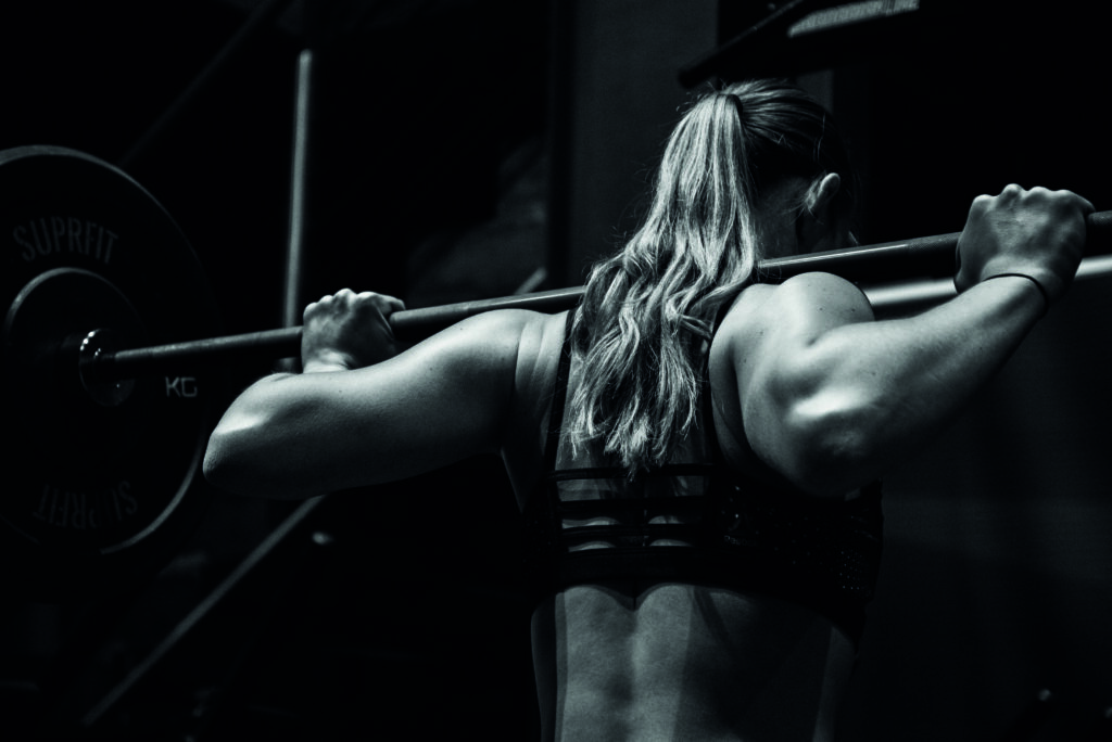 Frau von hinten mit einer Langhantel auf den Schultern