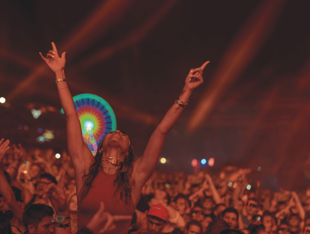 Eine Frau hebt beide Hände in einer Menschenmasse eines Festivals