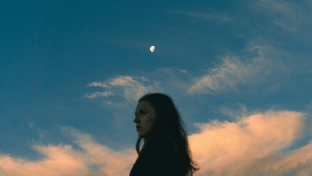 Frau vor einem Abend-Himmel mit Wolken und dem Mond