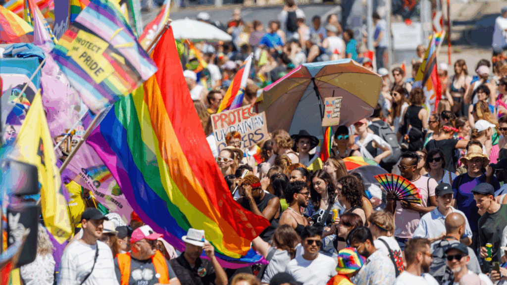 Eine Menschenmasse auf der Straße mit einer Regenbogenflaggen