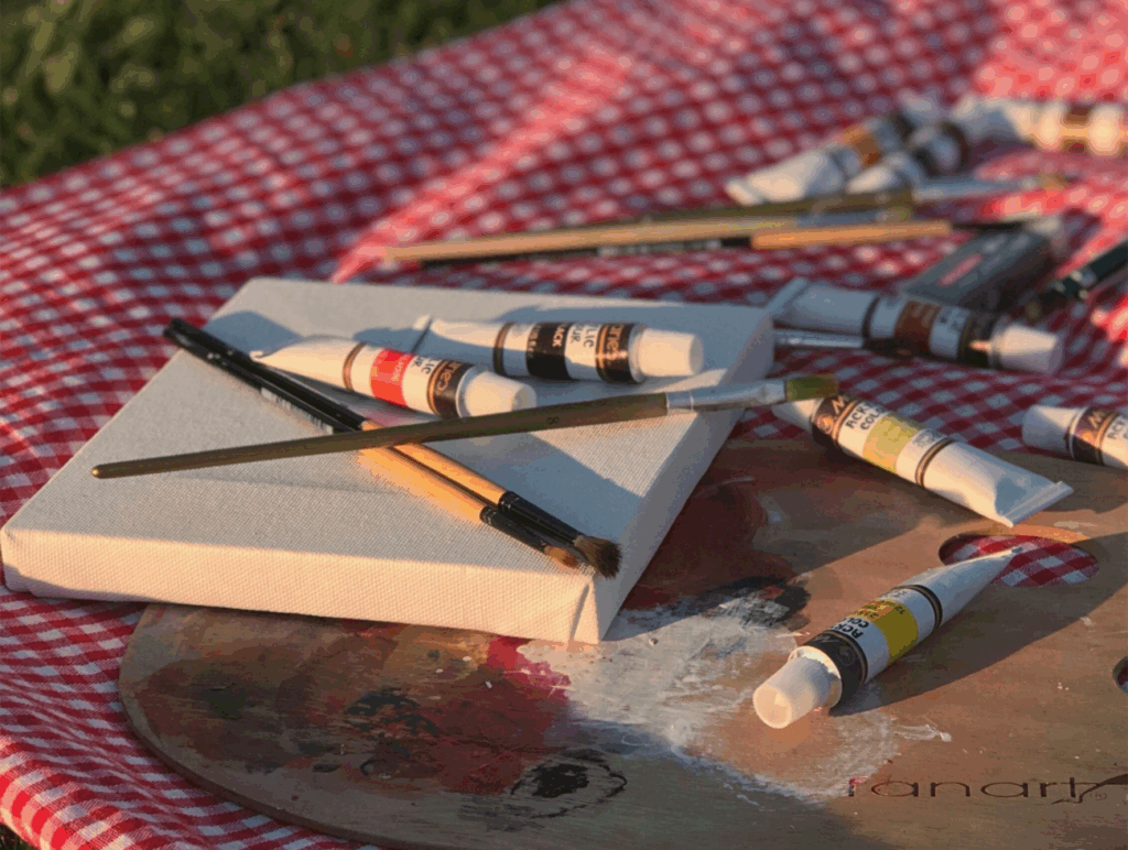 Malutensilien auf einer rot karierten Picknickdecke