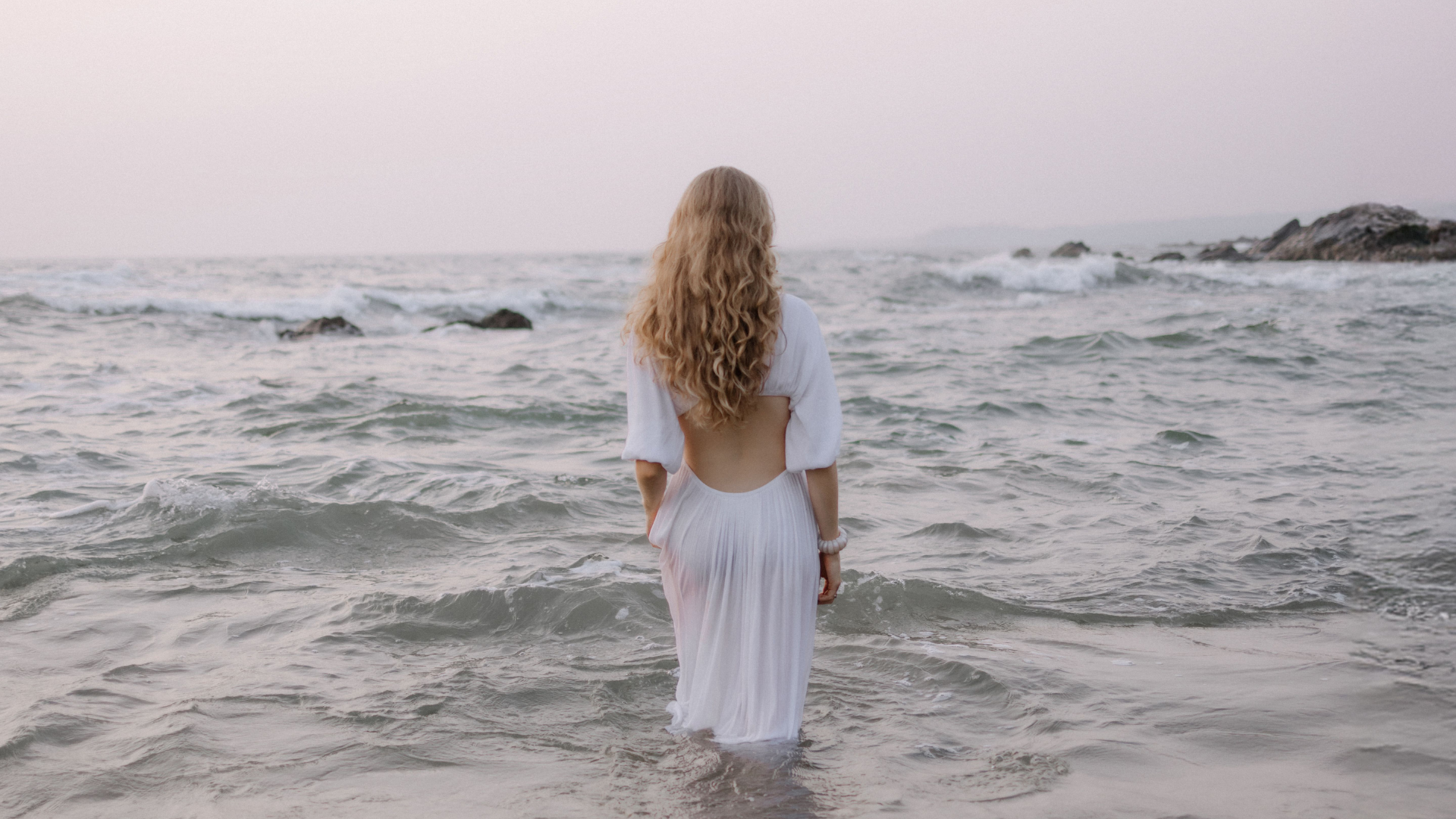 Eine Frau in einem weißen steht im Meer