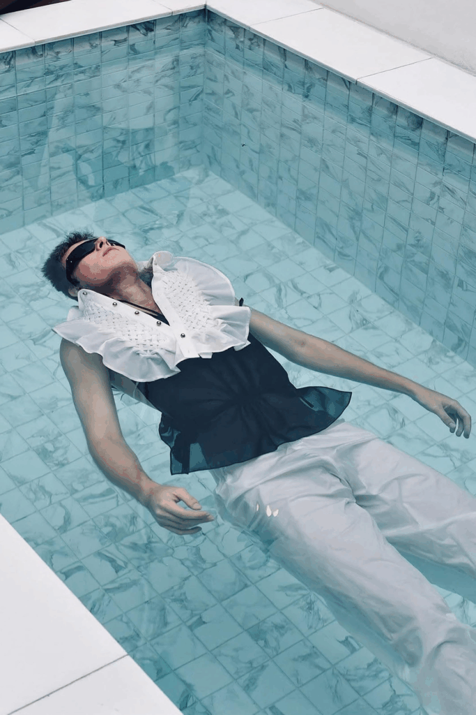 Ein Mann schwimmt am Rücken im Pool mit Kleidung von der Kollektion von Frank Weeneggsinn